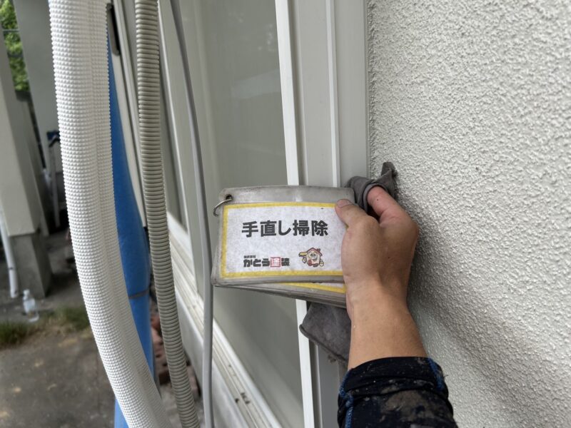 サッシに付着した塗料を拭き取っています。